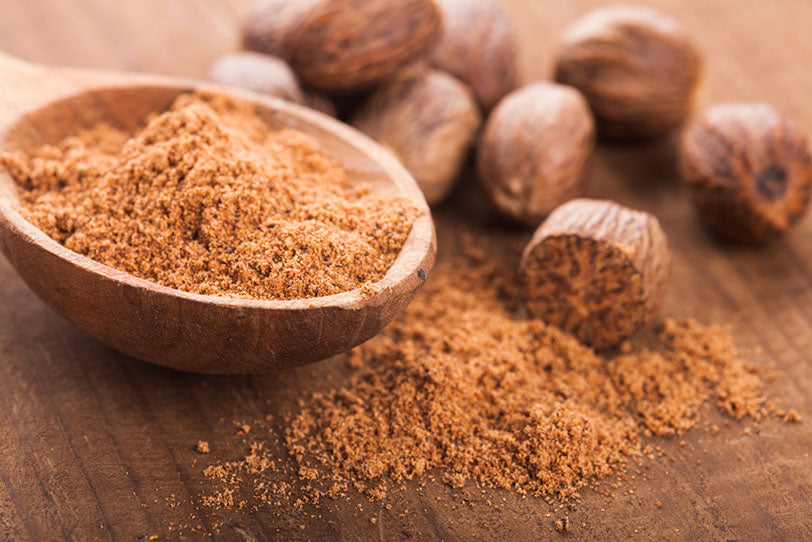 ground nutmeg spice wooden spoon