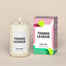 A lit Tennis League Homesick candle displayed next to its boxed packaging on a dark cream background.
