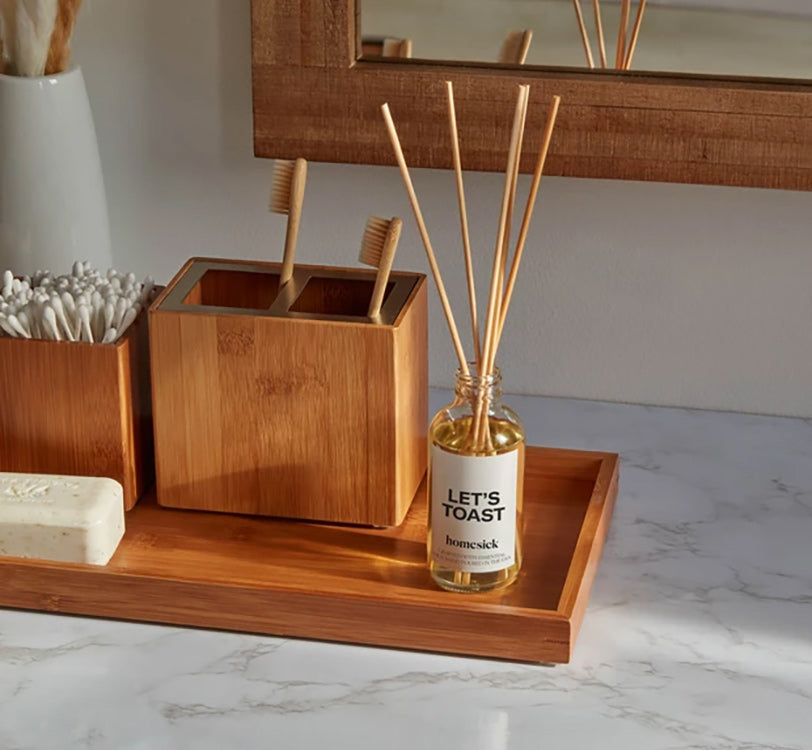 a lets toast reed diffuser next to a pair of toothbrushes on a bathroom sink counter