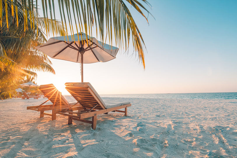 a couple of lounge chairs on a beach under an umbrella