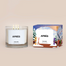 A lit Après Homesick candle displayed next to its boxed packaging on a dark cream background.