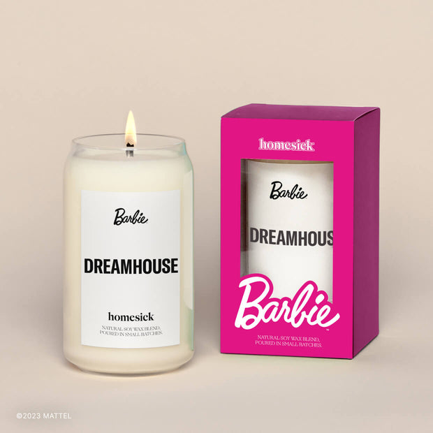 A lit Barbie Dream Homesick candle displayed next to its pink boxed packaging on a dark cream background.