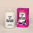 A lit Mojo Dojo Case House Homesick candle displayed next to its boxed packaging on a dark cream background.