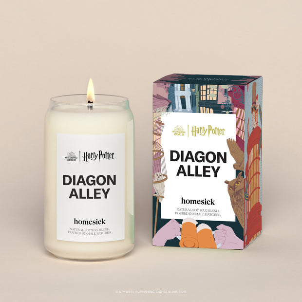 A lit Harry Potter Diagon Alley Homesick candle displayed next to its boxed packaging on a dark cream background.