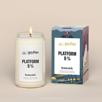 A lit Platform 3/4 Homesick candle displayed next to its boxed packaging on a dark cream background.