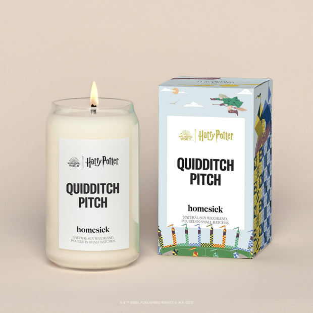 A lit Quidditch Pitch Homesick candle displayed next to its boxed packaging on a dark cream background.