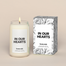 A lit In Our Hearts Homesick candle displayed next to its boxed packaging on a dark cream background.