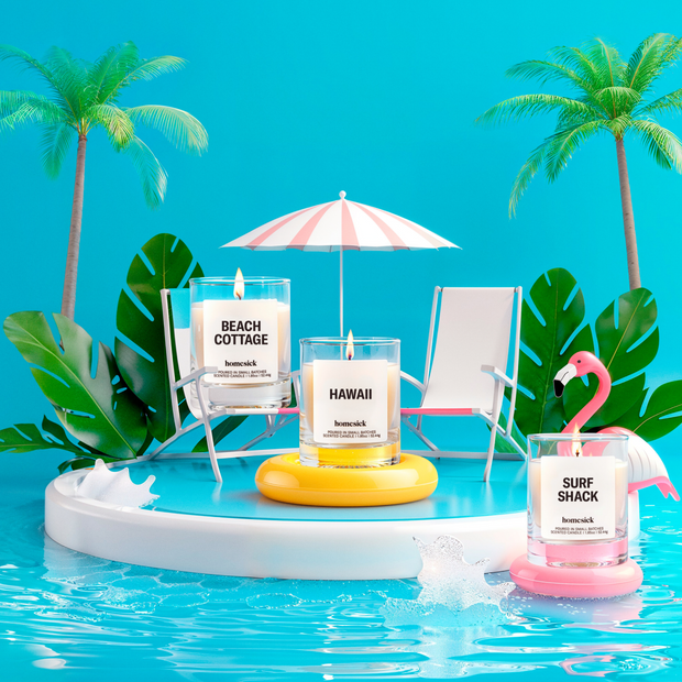 Lifestyle image of three mini candles labeled "Beach Cottage", "Hawaii", and "Surf Shack" in a beach vacation setting