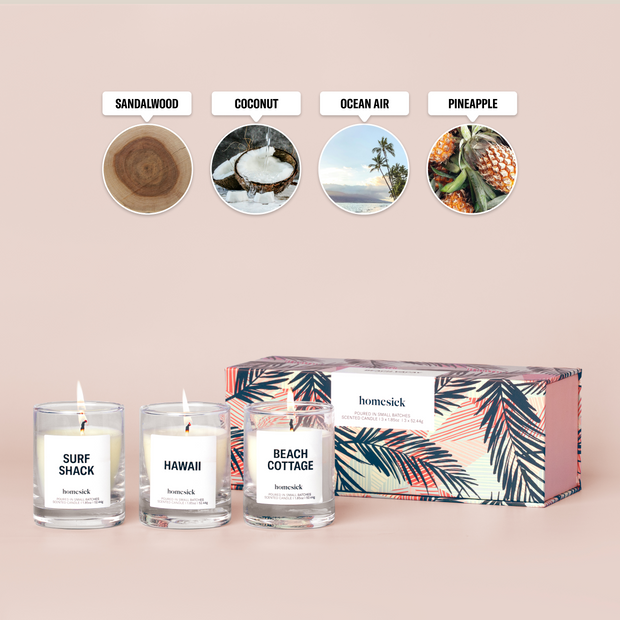 Three mini candles labeled "Beach Cottage", "Hawaii", and "Surf Shack" in front of a box on a cream background with featured scent notes labelled "Sandalwood", "Coconut", "Ocean Air", and "Pineapple"