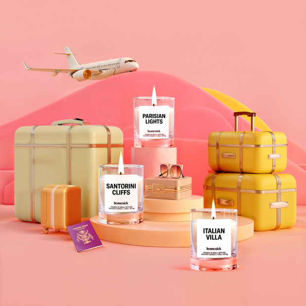 Lifestyle image of three mini candles labelled "Sanitorini Cliffs", "Italian Villa", and "Parisian Lights" in a travel setting