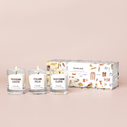 three mini candles labelled "Sanitorini Cliffs", "Italian Villa", and "Parisian Lights" and a box on a cream background