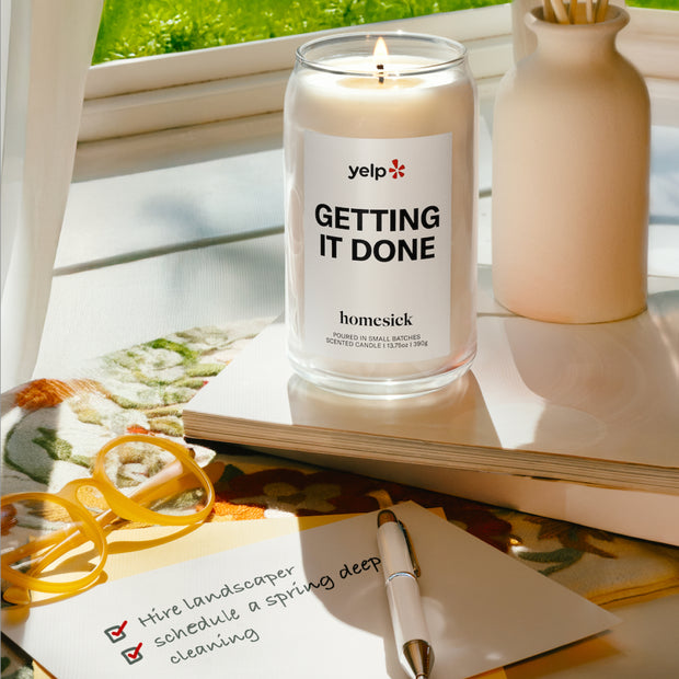 A lit Getting It Done candle next to a completed list of chores