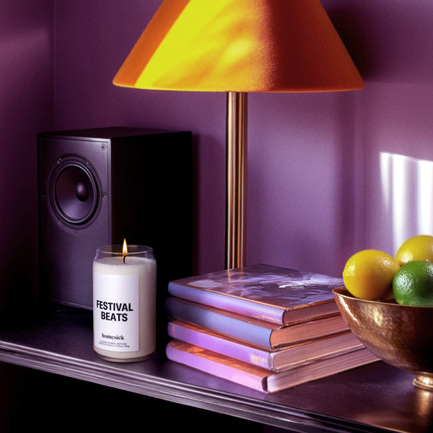 A lit Festival Beats Homesick candle on a well organized desk.