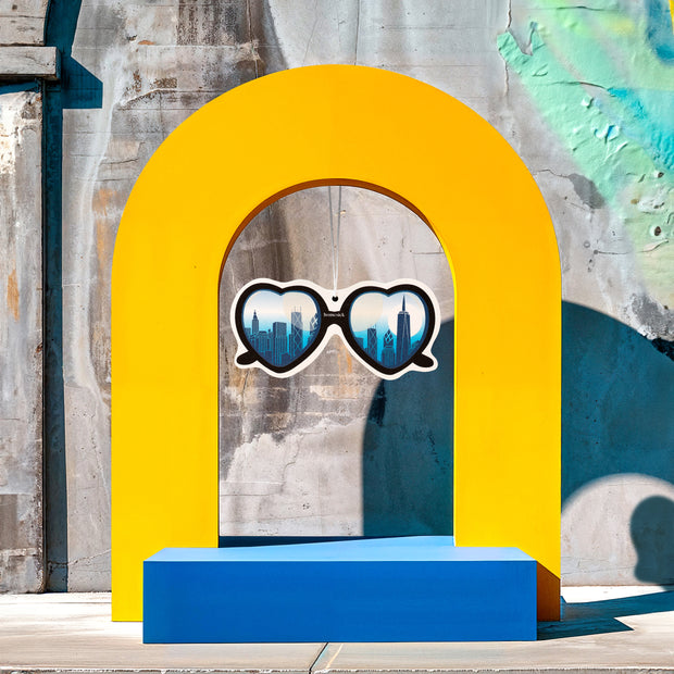 Lifestyle image of a car freshener in a city sidewalk themed scene