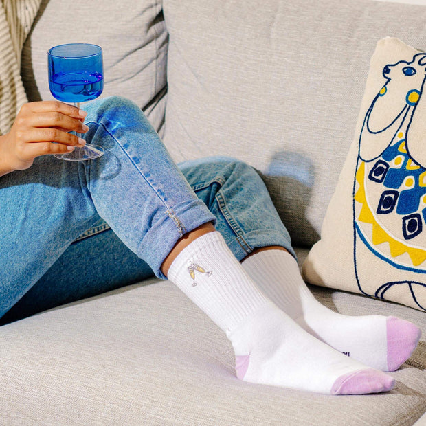 A lifestyle image of a woman sitting on a couch showing her let's toast high socks.