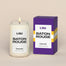 A lit LSU Baton Rouge Homesick candle displayed next to its boxed packaging on a dark cream background.