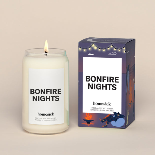 A lit Bonfire Nights Homesick candle displayed next to its boxed packaging on a dark cream background.