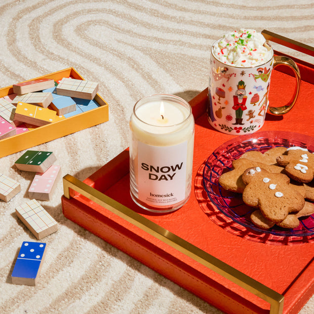 The Snow Day candle displayed inside a decor tray that also has a platter of gingerbread cookies and mug of hot cocoat.
