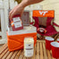 A stylized lifestyle image of the VT Blacksburg candles at a tailgate as if they were beers being pulled out of a cooler.