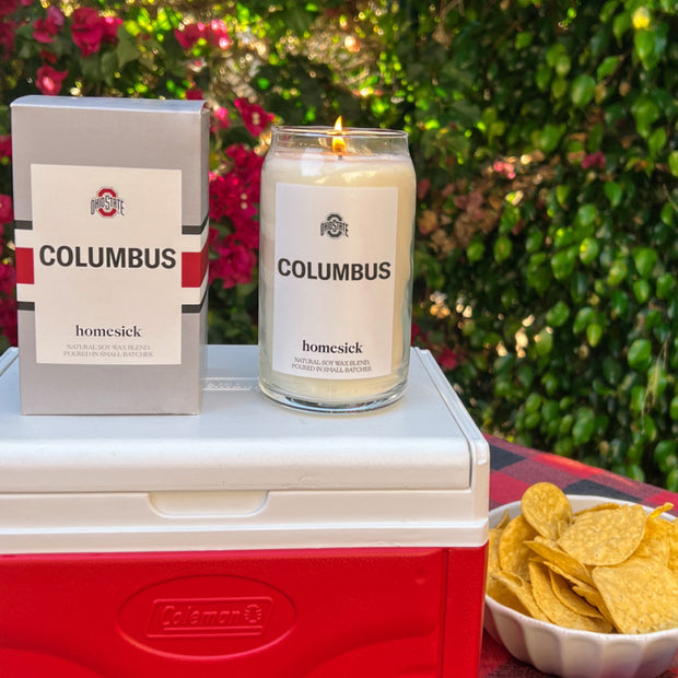 A Ohio State Columbus candle and its packaging on top of a tailgate cooler.