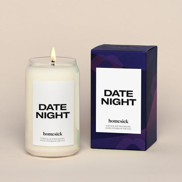 A lit Date Night Homesick candle displayed next to its boxed packaging on a dark cream background.