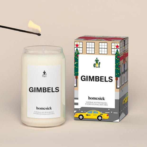 A lit Elf Gimbels Homesick candle displayed next to its boxed packaging on a dark cream background.