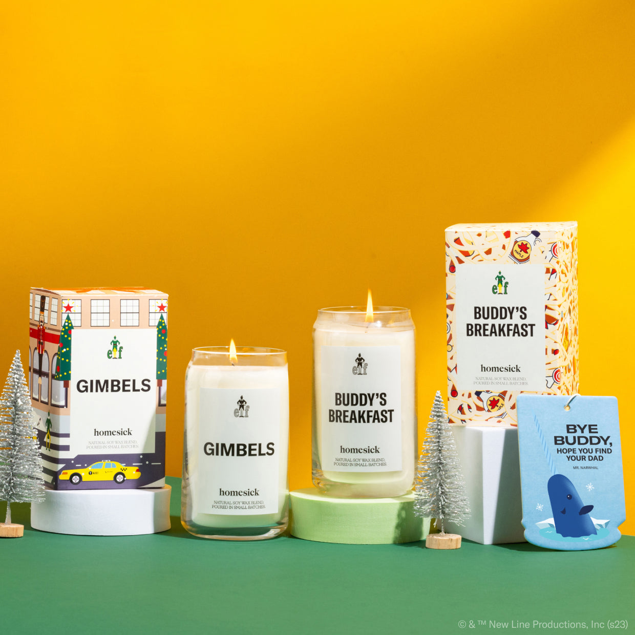 A group shot of all the products available in the Elf x Homesick collaboration. The products are shot on a green surface with a yellow background.