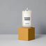 Evening unwind candle sitting on a gold box on a grey background.