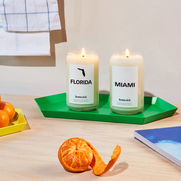 A side by side of the Florida and Miami candles on a green trinket dish. The dish is stylized in a kitchen setting.