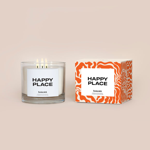 The 3-Wick Happy Place candle and its packaging shot on a dark cream background.