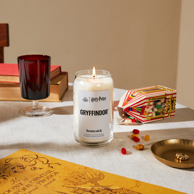A close up of the Gryffindor Candle on a table with various table props alongside it.