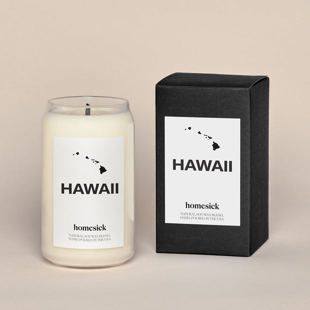 A lit Hawaii candle next the black box that it comes.