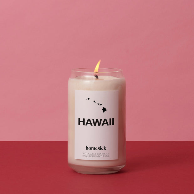 A lit Hawaii candle against a pink background.