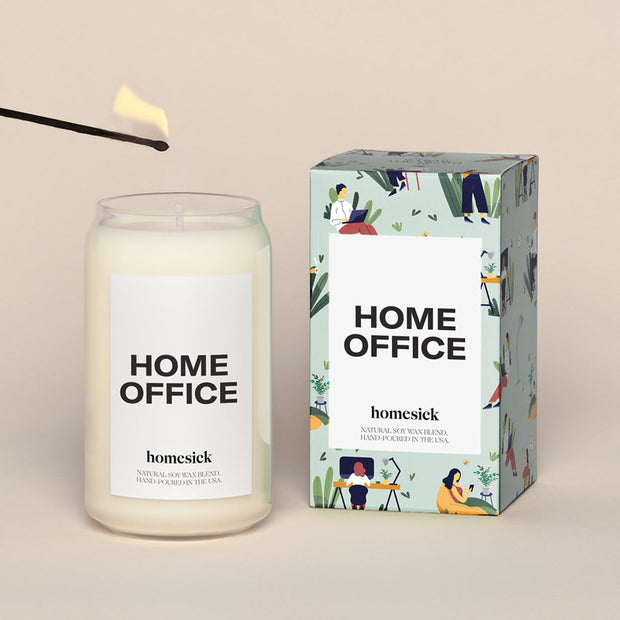 A lit Home Office Homesick candle displayed next to its boxed packaging on a dark cream background.