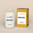 A lit Hufflepuff Homesick candle displayed next to its boxed packaging on a dark cream background.