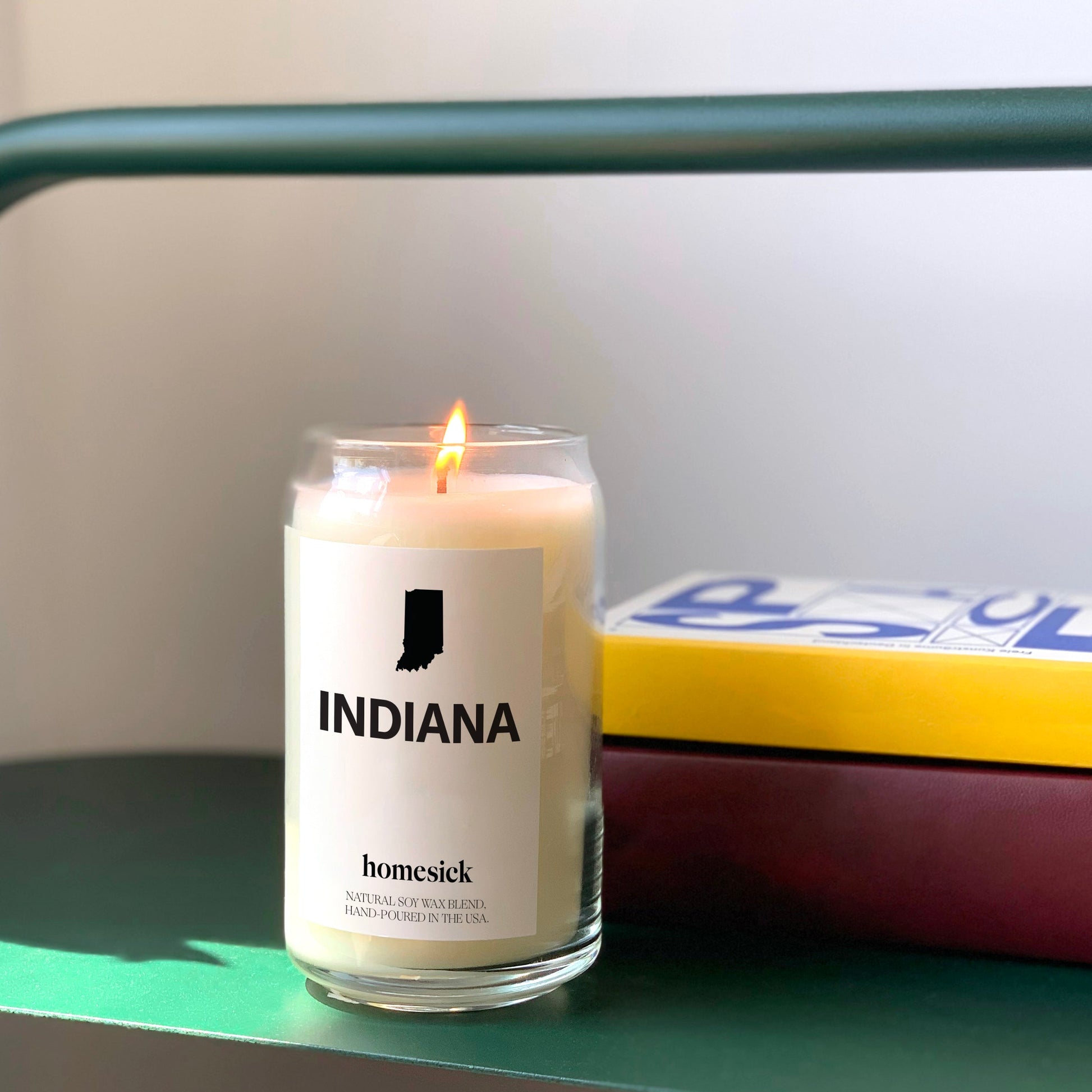 A closeup of the Indiana Candle shot on top of an Open Spaces green entryway rack.