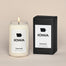 A lit Iowa Homesick candle displayed next to its boxed packaging on a dark cream background.