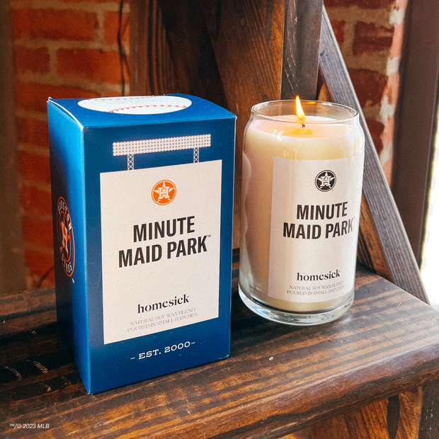 A corner shot of the Minute Maid Park candle and its packaging displayed on a wooden shelf. 
