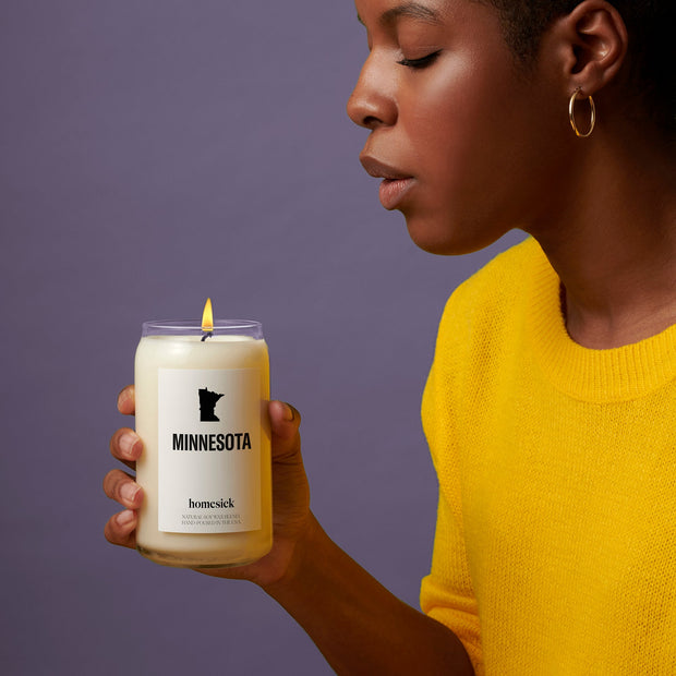 A model holding the Minnesota homesick candle about to blow it out.