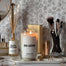 Lit spa-cation candles next to a beach cottage reed diffuser on a vanity with a calm setting.