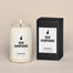 A lit New Hampshire Homesick candle displayed next to its boxed packaging on a dark cream background.