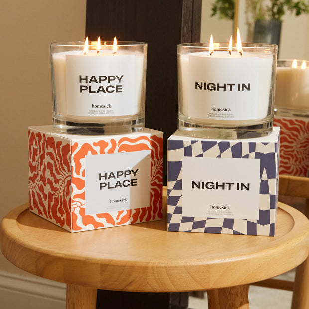 A group shot of two 3-Wick Candles on top of their boxed packages.