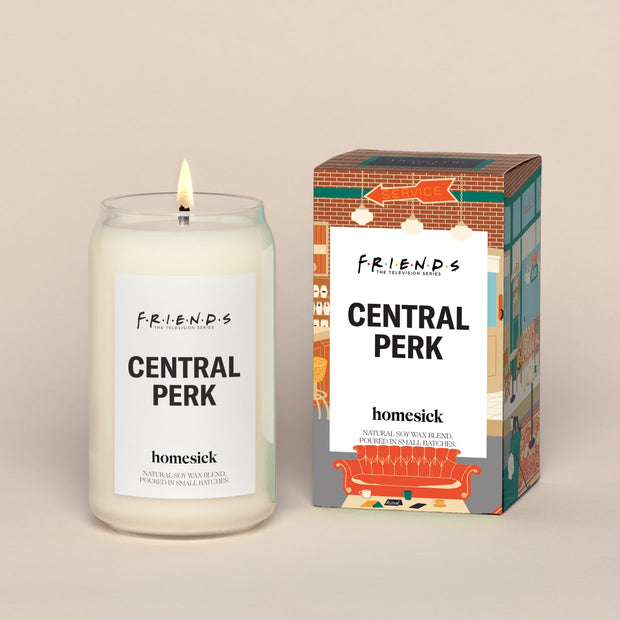 A lit Central ParkHomesick candle displayed next to its boxed packaging on a dark cream background.