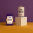 A deep yellow surface with a deep purple background. There is a LSU Baton Rouge candle on a white pedestal next to a packaged candle.