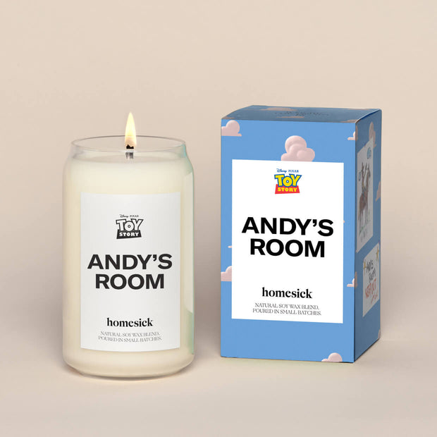 A lit Andy's Room Homesick candle displayed next to its boxed packaging on a dark cream background.