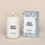 A lit Ski Trip Homesick candle displayed next to its boxed packaging on a dark cream background.
