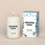 A lit Snow Day Homesick candle displayed next to its boxed packaging on a dark cream background.