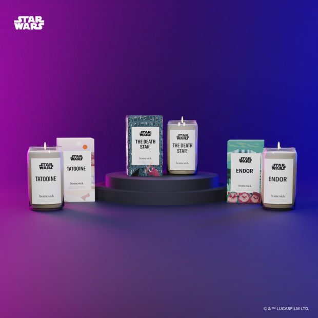 A group product shot of the Star Wars Candles and their boxed packaging. Left to right are the following candle scents: Tatooine, The Death Star, Endor. Shot on a purple blue gradient background.