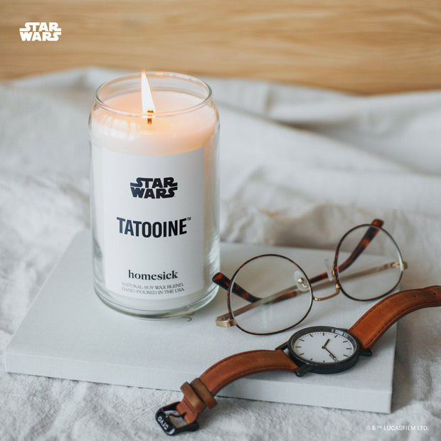 A close up shot of the Tatooine candle displayed on top of a white notebook with glasses and a watch on the corner of the notebook