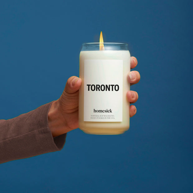 A hand holding the Toronto candle in front of a blue background.